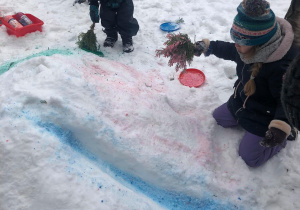Dzieci przy użyciu naturalnych gałązek malowały farbami na śniegu